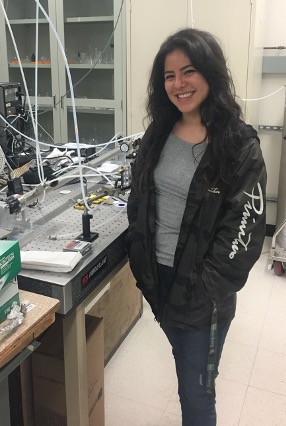 Ph.D. Student Stephanie L. Mora Garcia with her spectroscopic instrument, the Incoherent Broadband Cavity Enhanced Absorption Spectrometer (IBBCEAS).